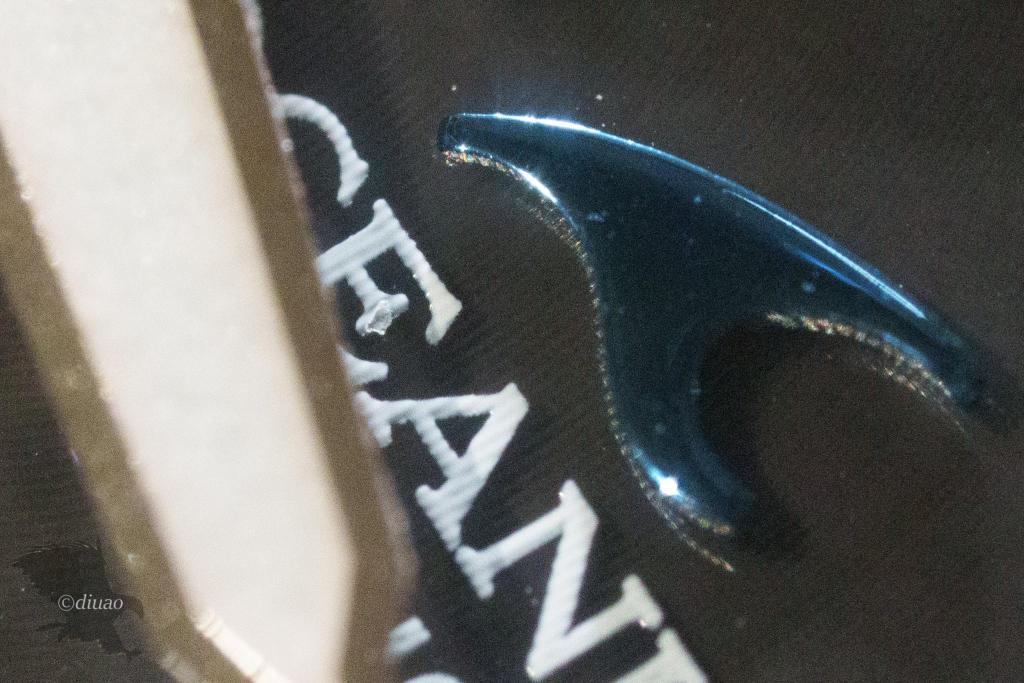 SEL100M28GMとSEL20TCで撮影した時計のロゴを拡大したもの